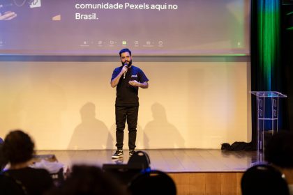 Homem fala ao microfone em um palco durante uma apresentação pública
