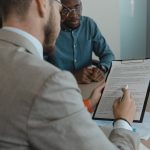 Recrutador analisa documentos de uma candidata durante uma entrevista de emprego em um escritório