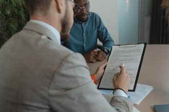 Recrutador analisa documentos de uma candidata durante uma entrevista de emprego em um escritório
