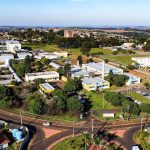 Vista aérea de um campus universitário, com edifícios acadêmicos e áreas verdes ao redor.