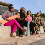 Grupo de idosos reunido ao ar livre, com colchonetes de yoga, durante uma atividade de bem-estar.