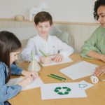 Crianças aprendem sobre reciclagem com uma professora durante atividade educativa em sala de aula.