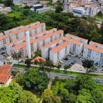 Vista aérea de um conjunto residencial de apartamentos cercado por áreas verdes.