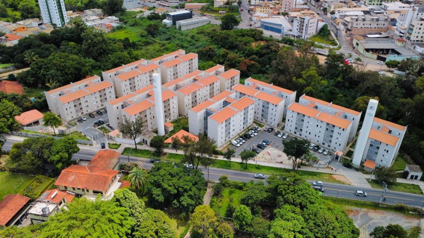 Vista aérea de um conjunto residencial de apartamentos cercado por áreas verdes.